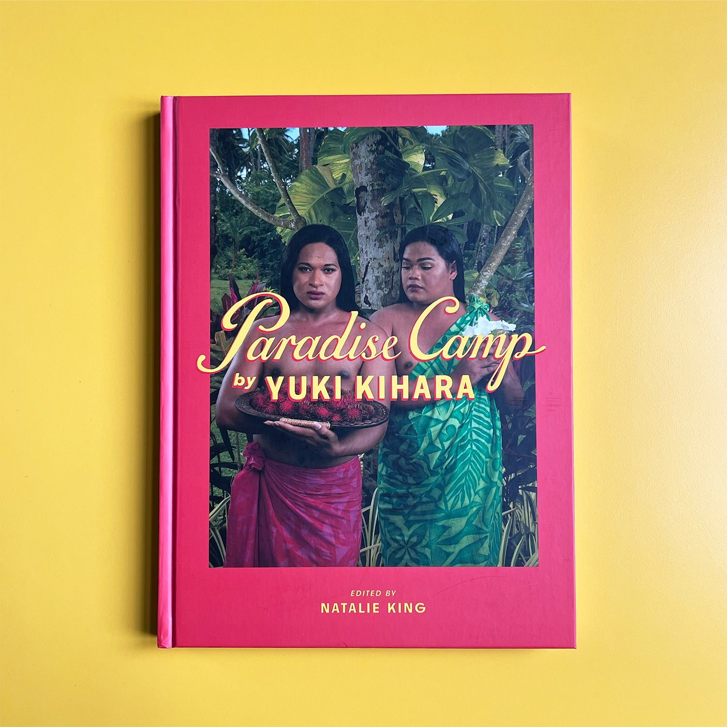 Book cover of 'Paradise Camp' by Yuki Kihara with a pink border on a yellow background