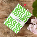 Lifestyle of notebook on a wooden surface. The notebook has green squiggly lines and a belly band with the Aarven branding.