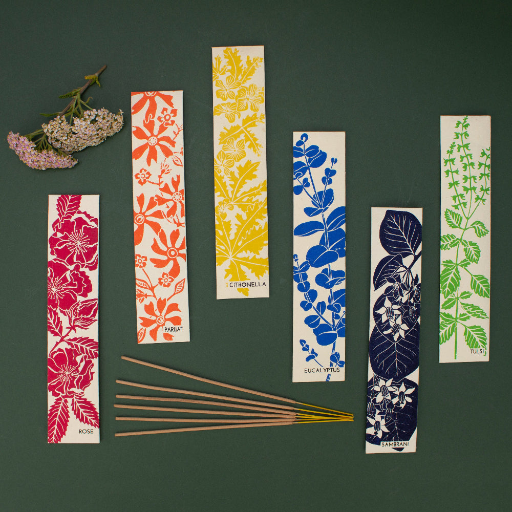 Set of colorful incense packets with floral and leaf patterns on a dark green background.