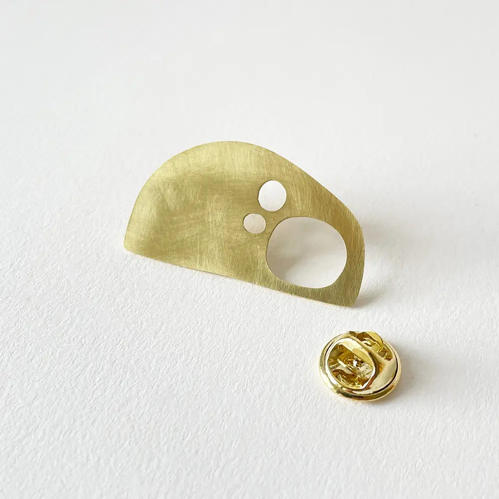 Gold metal brooch with a unique design on a white background
