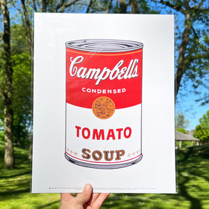 A person holding a print of Andy Warhol's Campbell's Tomato Soup