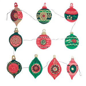 The image shows a collection of handmade paper ornaments hanging from a string. They are decorated with intricate patterns and colours, including red, green, gold, and pink. Some ornaments have geometric shapes, while others feature floral designs. 