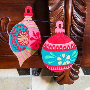 Two baubles in the garland hanging in front of a wooden piece of furniture