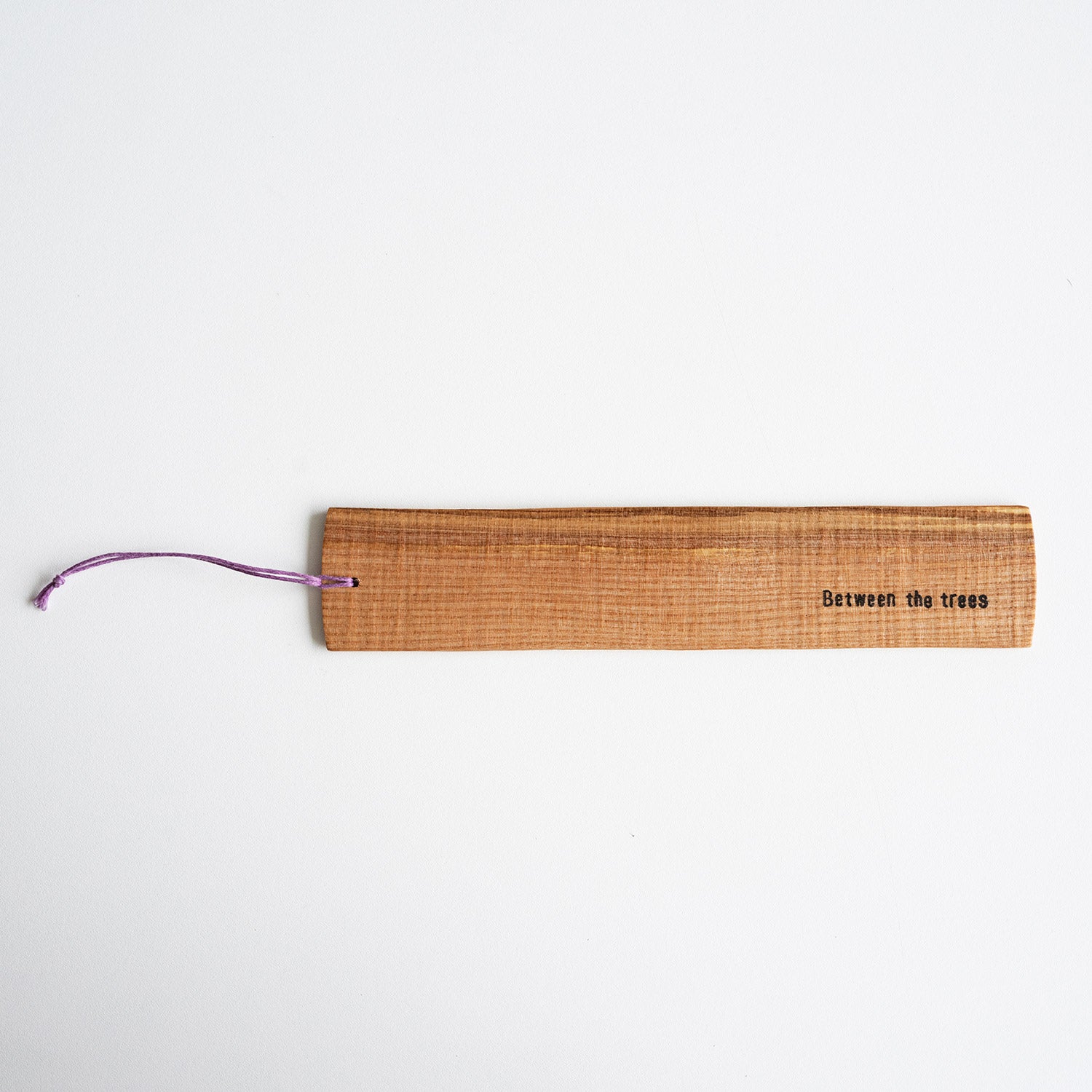 Wooden bookmark with 'Between the trees' text on a white background