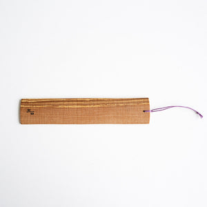 Wooden paddle with a purple cord on a white background