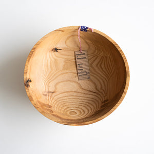Wooden bowl with a visible brand tag on a white background