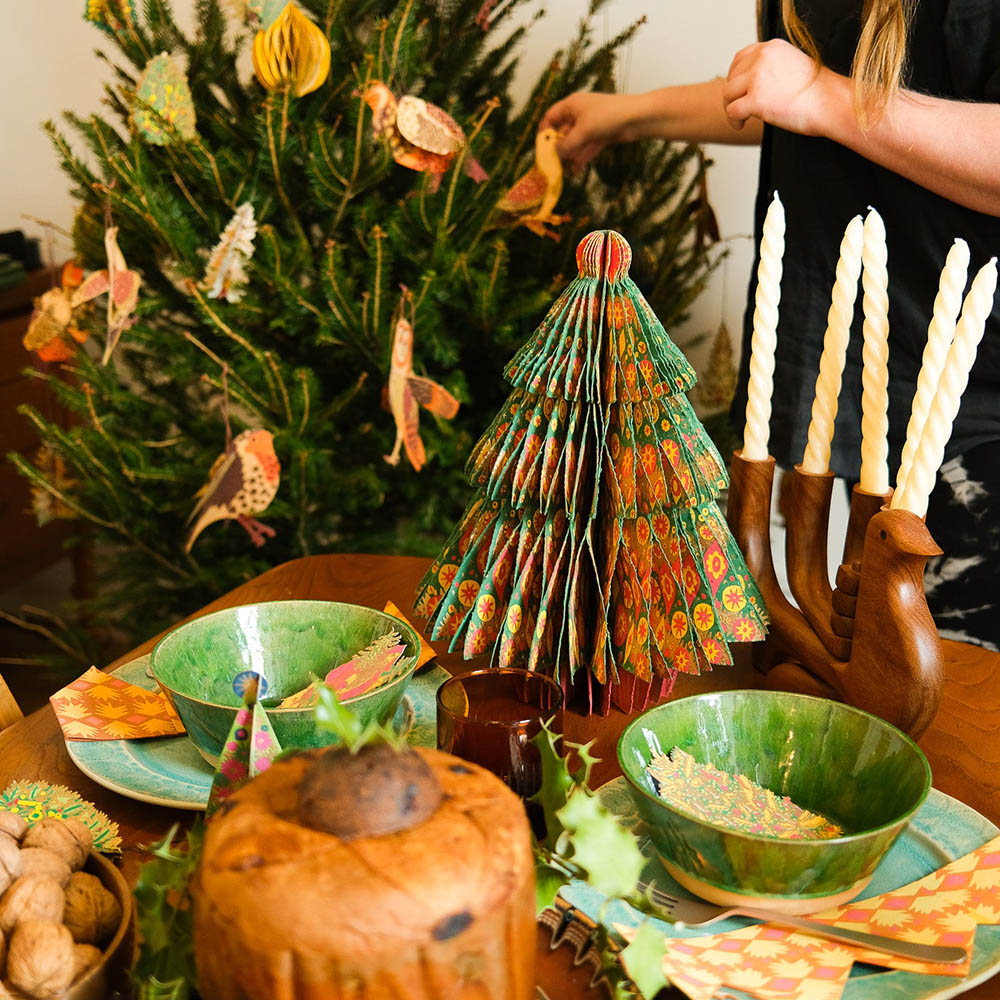 Decorative table setting with a paper tree, candles, and festive decorations.