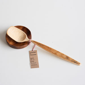 Wooden spoon and wooden rest with a tag on a light gray background