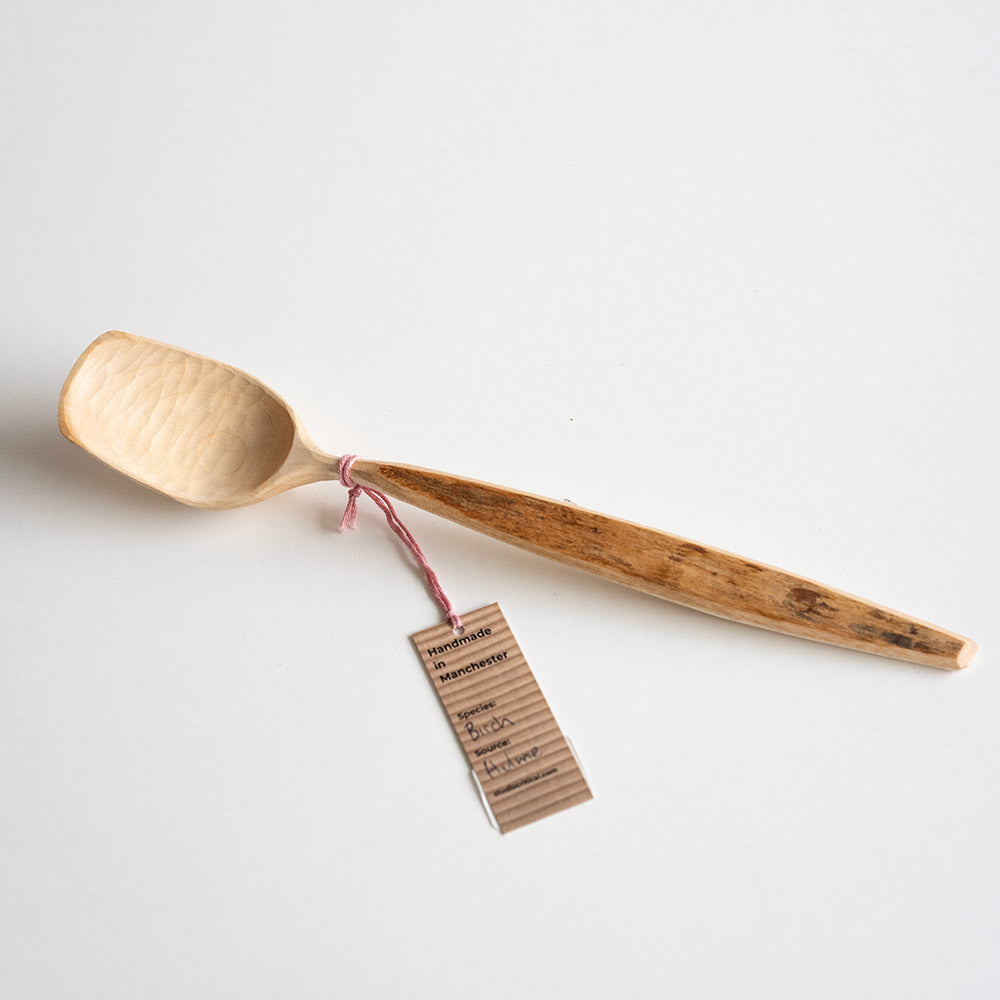 Wooden spoon with a tag on a light gray background