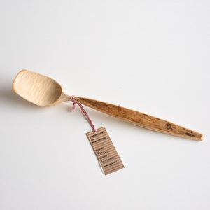 Wooden spoon with a tag on a light gray background