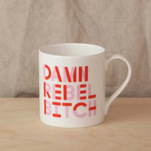 White mug with pink and red typographic font saying 'Damn Rebel Bitch'.