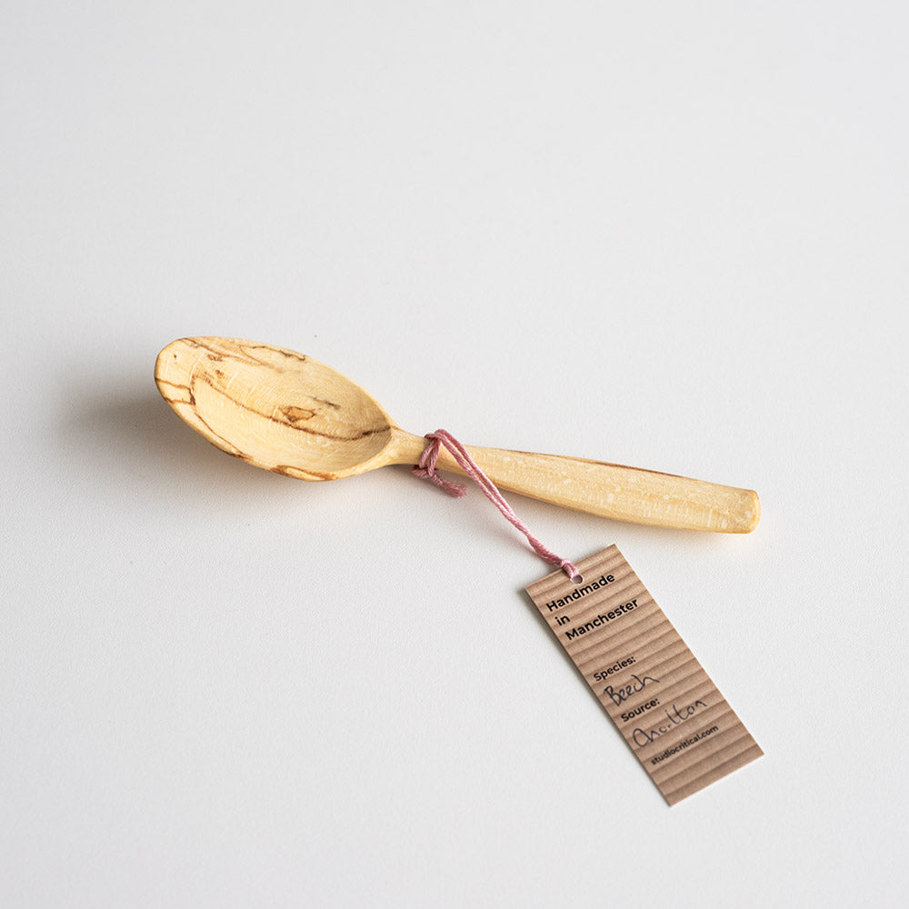 Wooden spoon with a tag on a light gray background