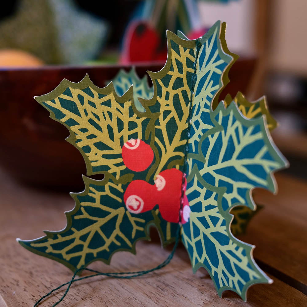 Decorative holly leaves with berries on a wooden surface