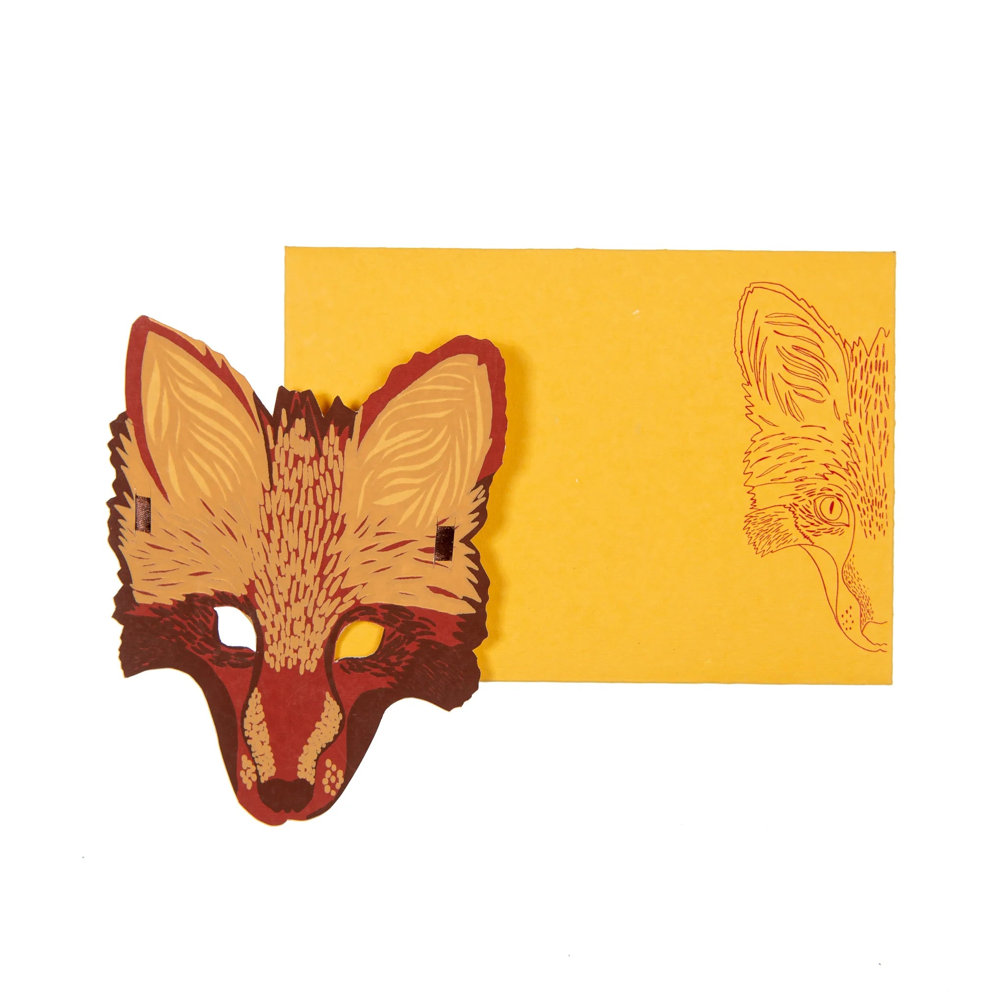 Hand printed greetings card, printed and cut in the shape of a fox's face. Above a yellow envelope with an illustration of a fox on it.