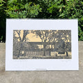 Linocut print featuring the Whitworth Cafe - presented upright in front of some green foliage