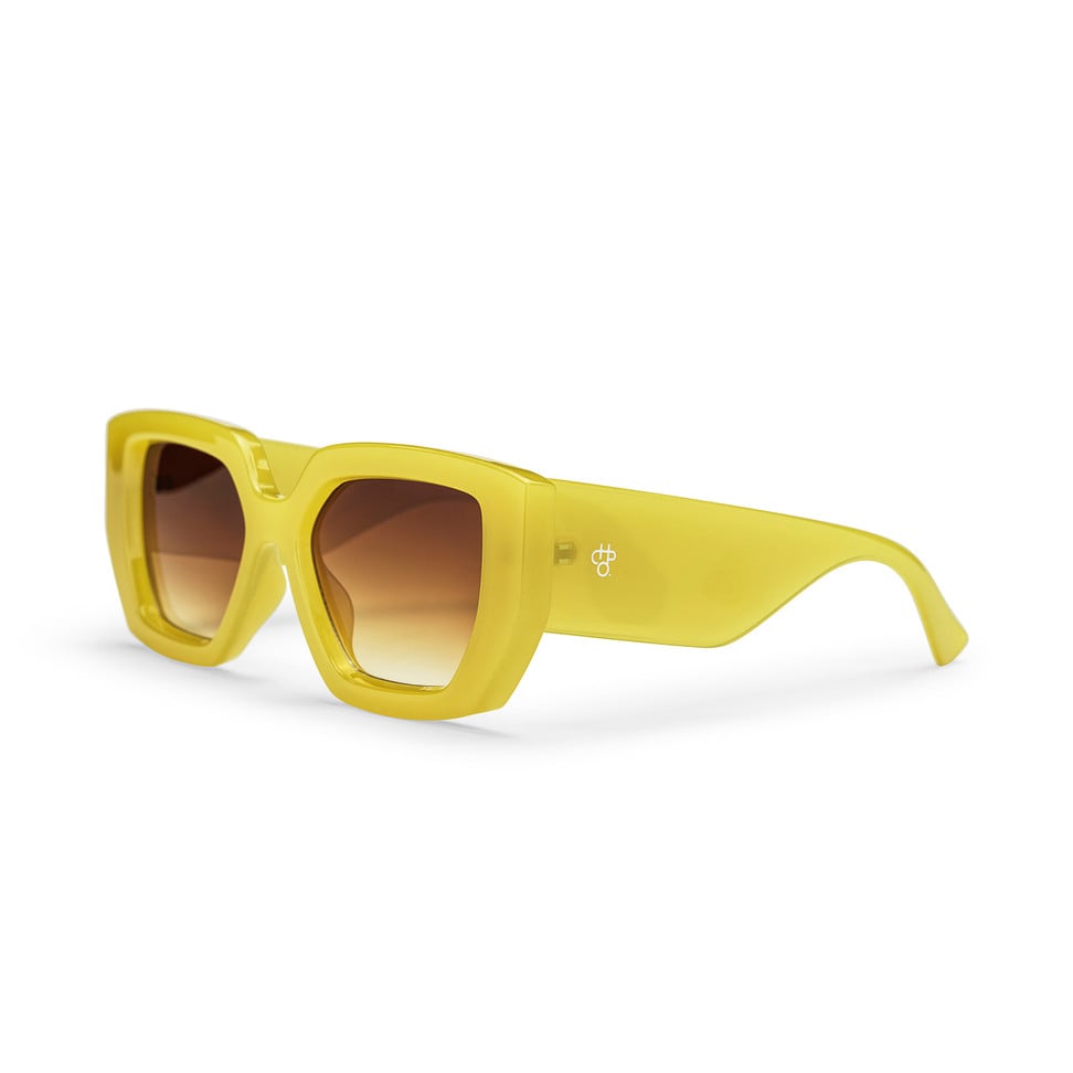 Yellow sunglasses with brown gradient lenses on a white background