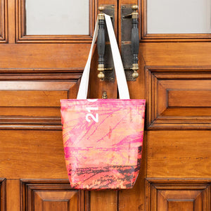 Bag with red, orange and yellow pattern detail. Photographed hung up on a large brown door.
