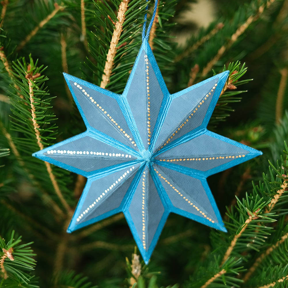 Blue star decoration hanging on a Christmas Tree