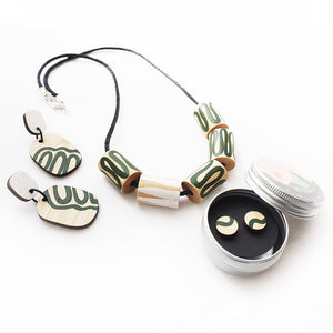 A selection of wooden jewellery with green hand-painted swirls