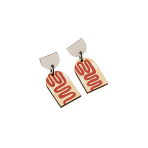 Dangly earrings photographed against white background. The earrings are each in two pieces, the top a white semi-circle and the bottom an arch-shape with hand-painted red swirls.