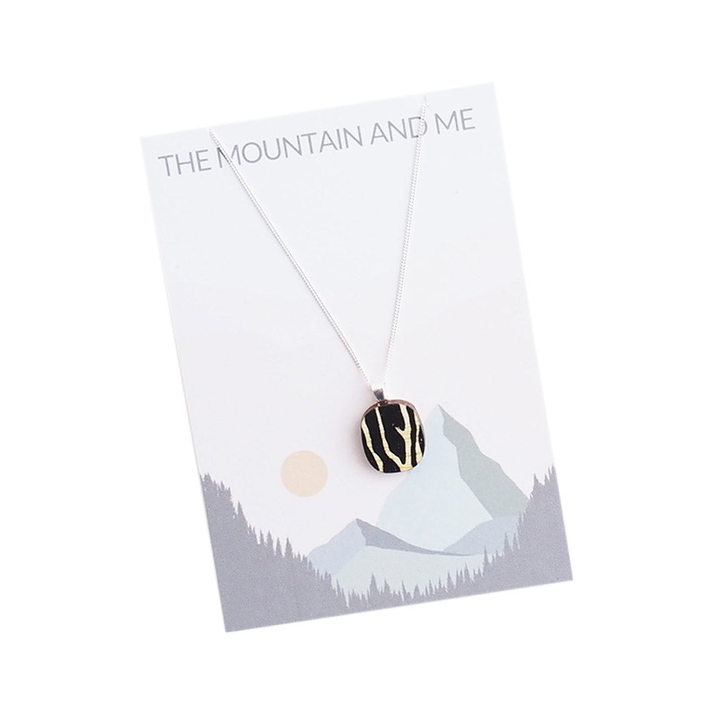 Necklace with a black and white pendant on a card with 'The Mountain and Me' text