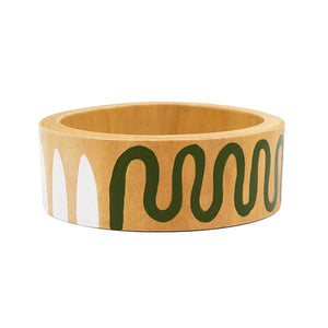 Hand-painted bangle with green and white swirls. Placed in front of a white background.