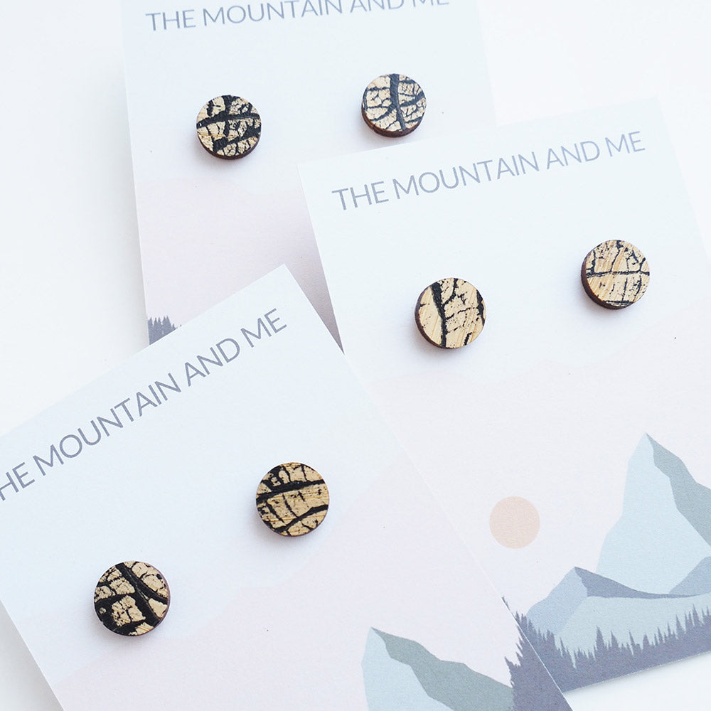 Three sets of wooden stud earrings with tree branch style patterns, presented on The Mountain and Me branded backing card.
