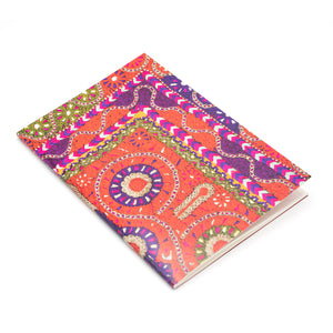 Notebook featuring a photographic detail of a red, purple and orange embroidered dress. The notebook is photographed against a white background.