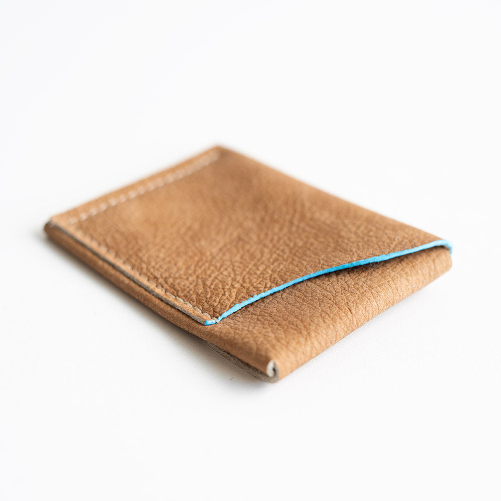 Brown leather wallet with blue stitching on a white background
