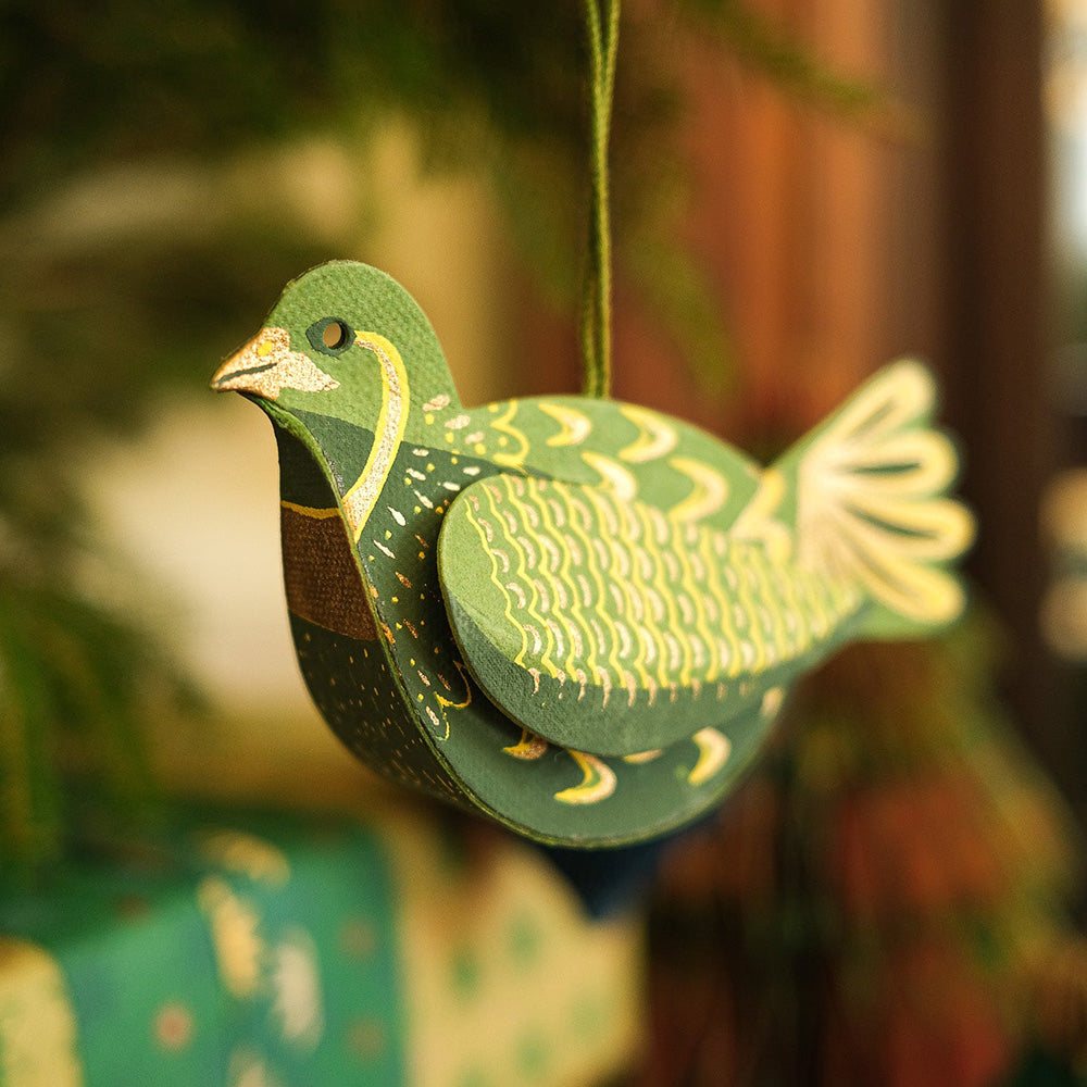 Decorative green and yellow bird ornament hanging against a blurred background