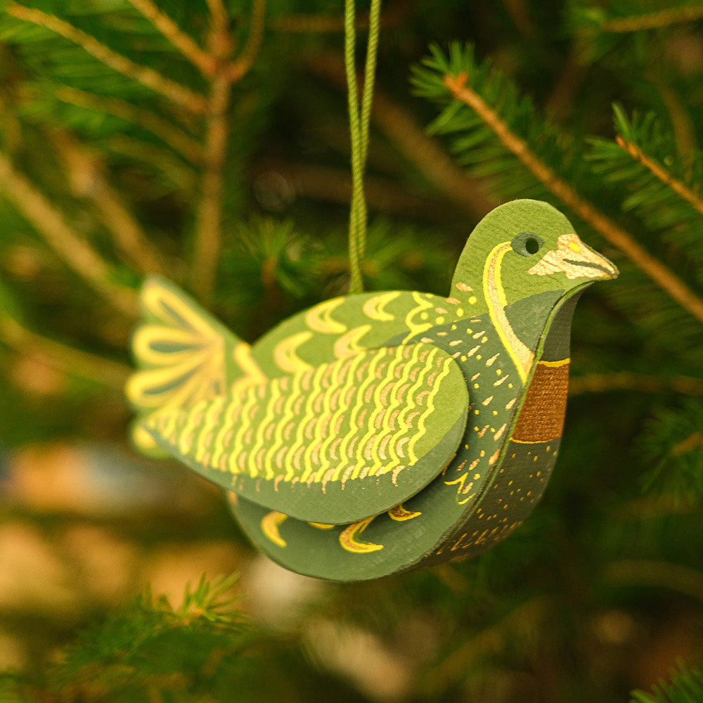 Decorative green and yellow bird ornament hanging on a Christmas tree.