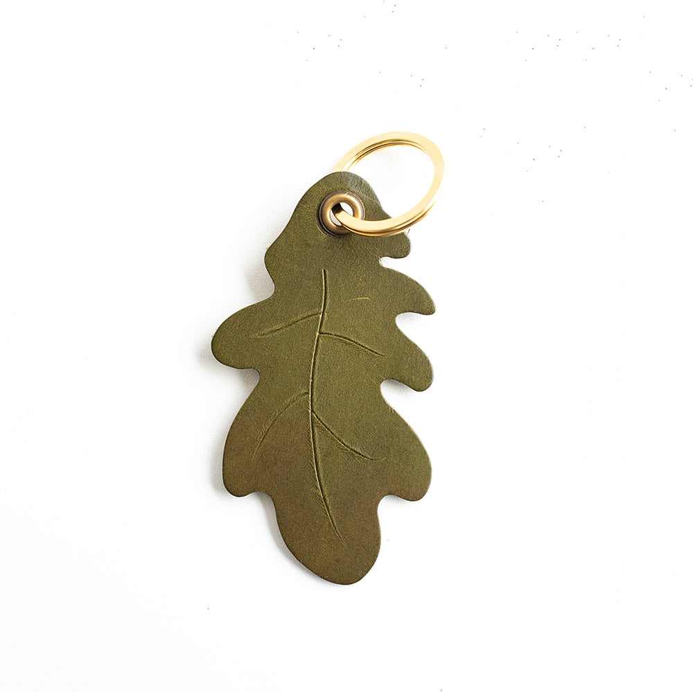 Green leaf-shaped keychain with a gold ring on a white background