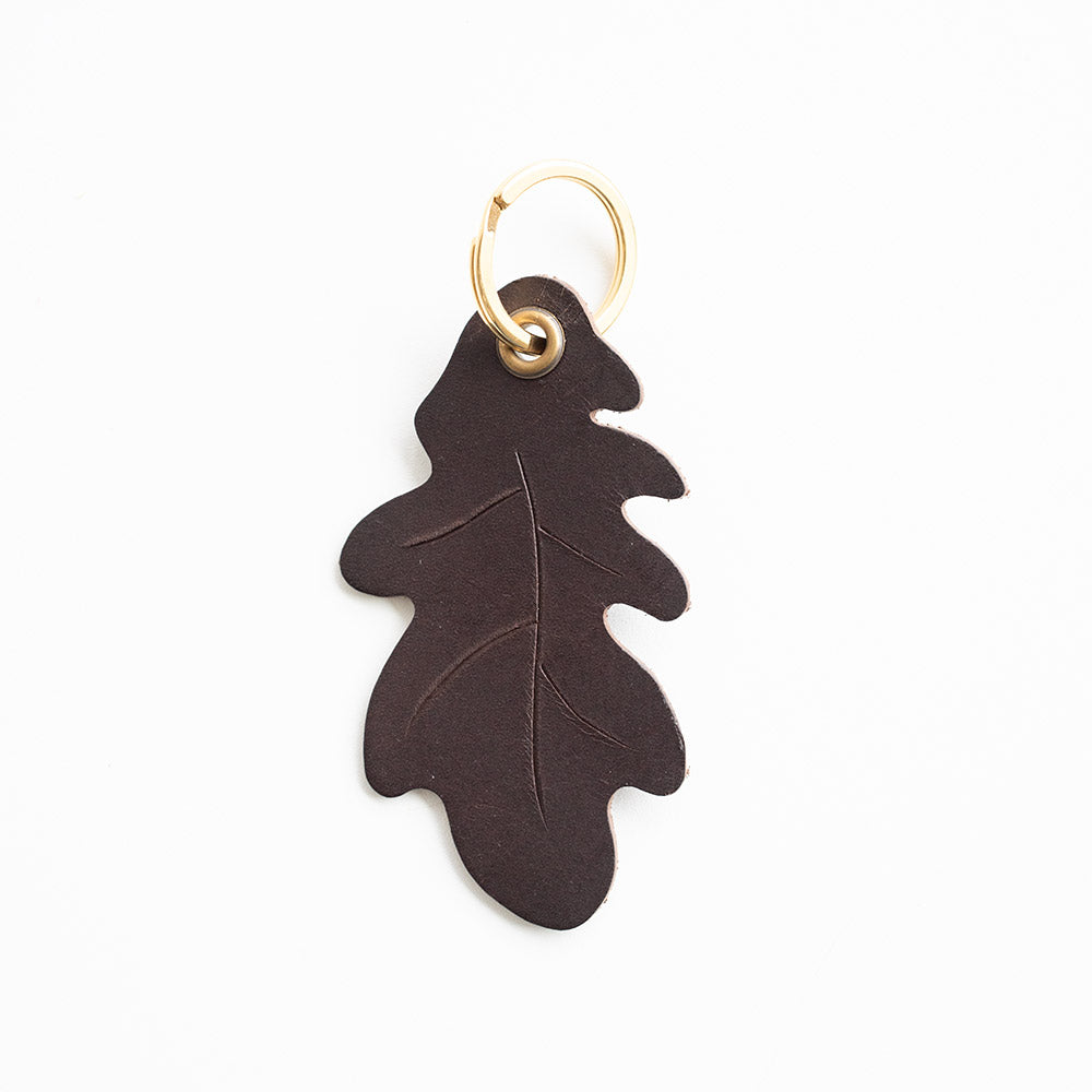 Brown leaf-shaped keychain with a gold ring on a white background
