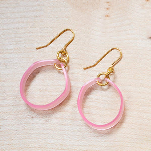 Pink acetate hoop earrings with gold hook fastening - photographed laid flat against a wooden board.