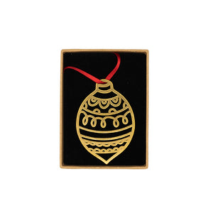 Brass decoration in the shape of a bauble, photographed in a brown box in front of white background.