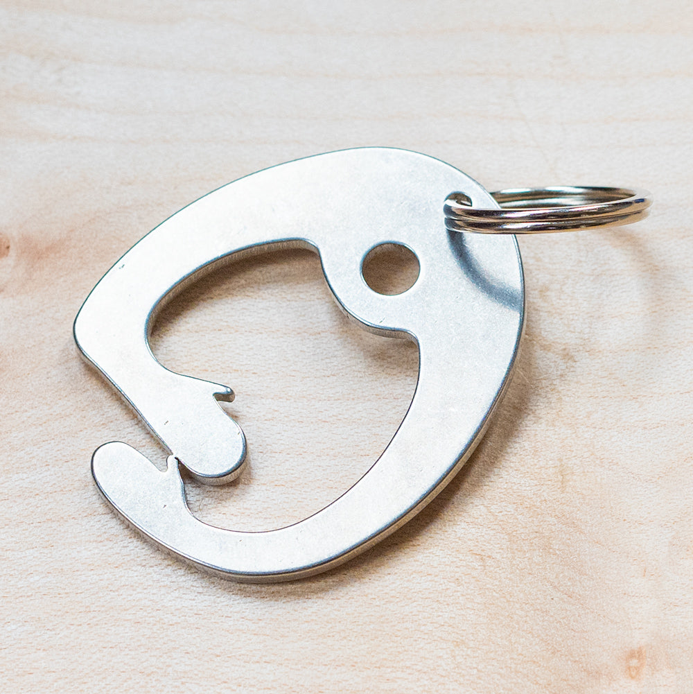 A silver key ring bottle opener photographed on wood