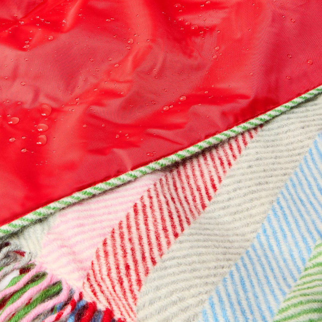 Close-up of a colourful woven fabric with red, green, blue, and beige patterns.