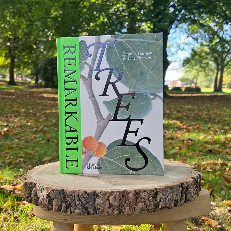 Book titled 'Remarkable Trees' on a wooden stand with a park background