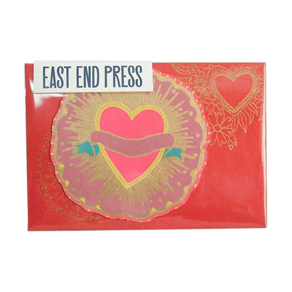 Circular greetings card with a love heart on it, placed on top of a red rectangular envelope.