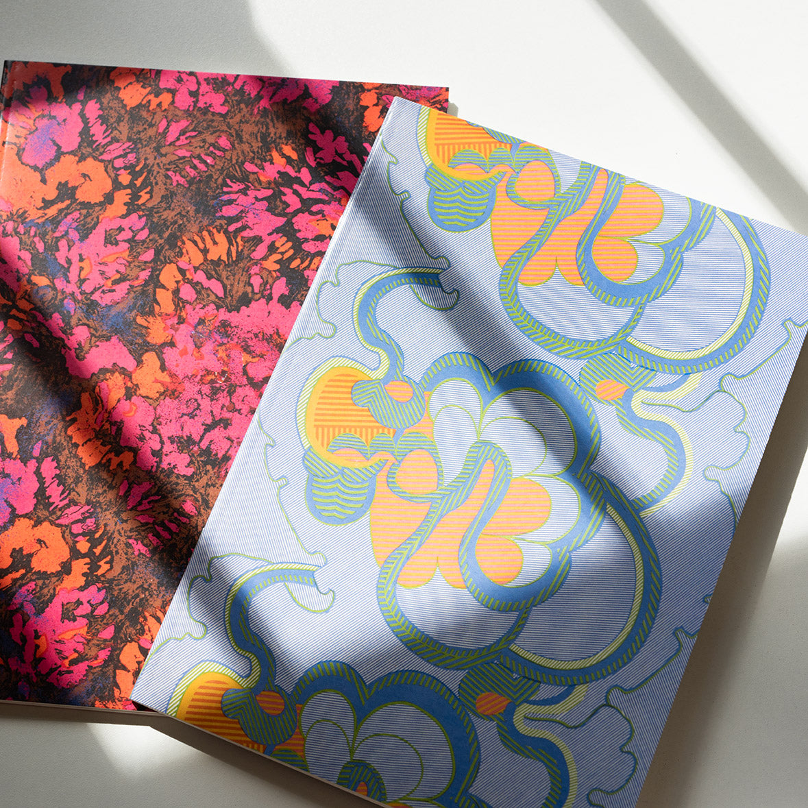 Two notebooks featuring Shirley Craven designs laid out flat on a table.