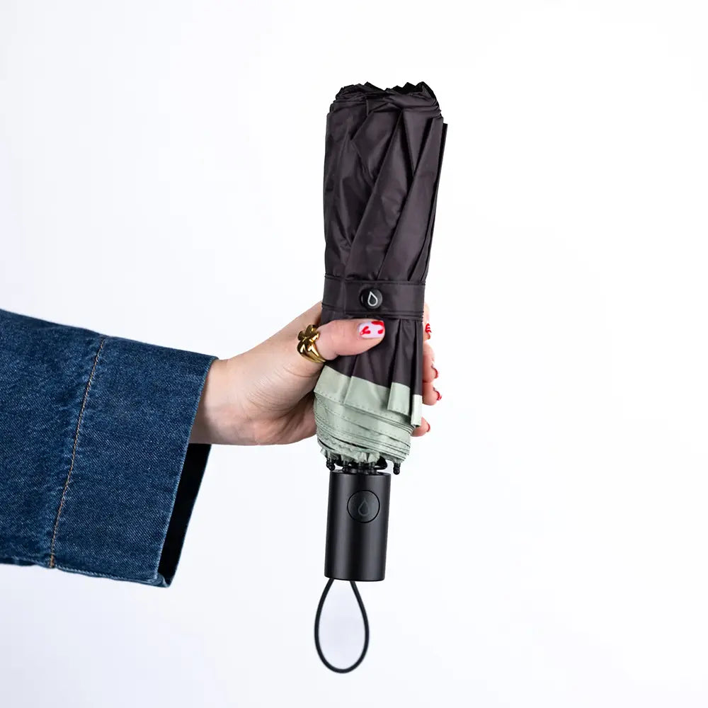 Hand holding a black umbrella with a white background