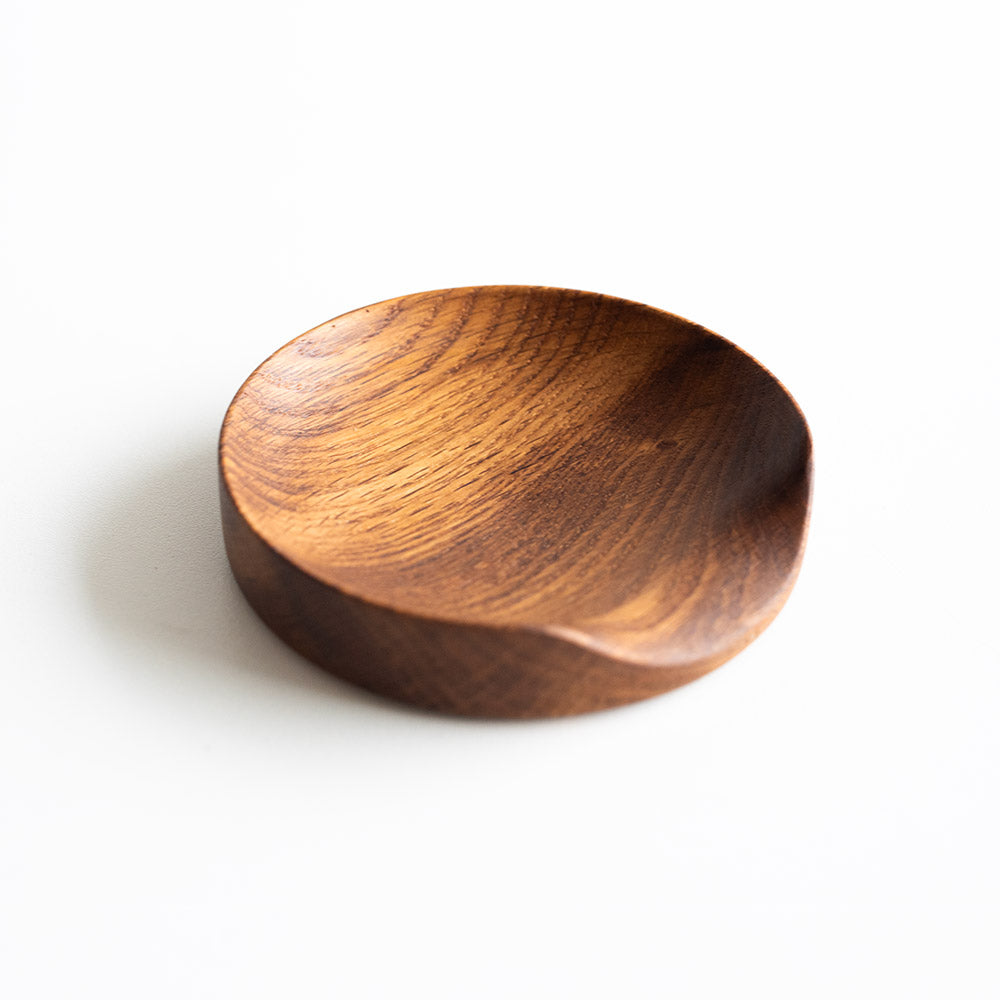 Wooden spoon holder with dipped edge against a light gray background.