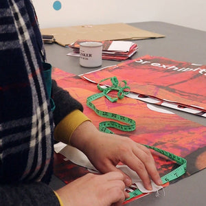 Someone measuring an exhibition banner that has been cut into pieces.