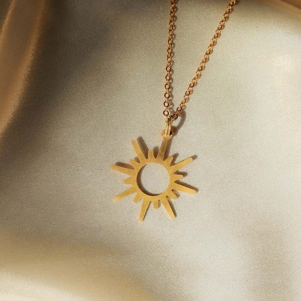 A gold sun pendant necklace with a minimalist design. The pendant features a simple, circular outline with radiating sun rays.