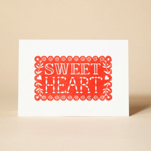 Linocut greetings card with SWEET HEARD at the centre in red typography.