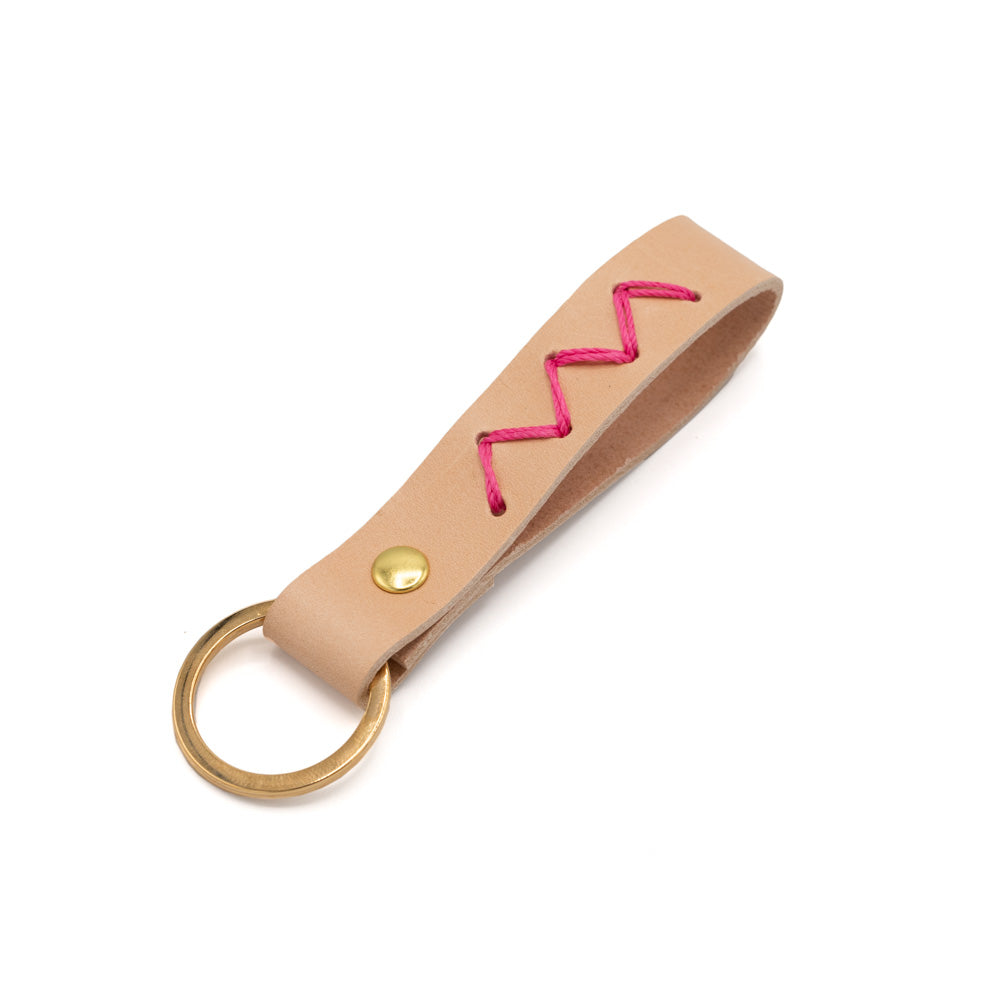 Pale pink leather keyring with zig-zag pink stitch. White background.