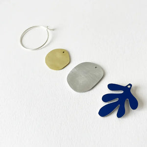 Mixed metal shapes of the earrings all placed separately on a white surface.