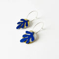 Pair of mixed metal earrings, each metal has a different shape and they are tied together with a silver hoop. White background.