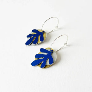 Pair of mixed metal earrings, each metal has a different shape and they are tied together with a silver hoop. White background.