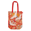 Red and orange tote bag featuring cranes pattern artwork. Red handle. Presented on a white background.